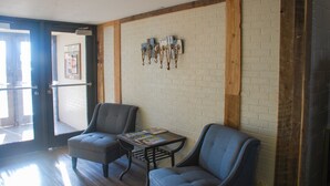 A room with two chairs, a small table, and a wall-mounted coat rack. - Sunlac Inn (Lakota)