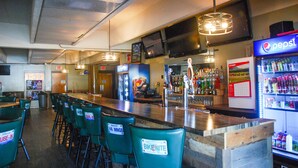 A bar area with green chairs, a Pepsi refrigerator, and a bar counter. - Sunlac Inn (Lakota)
