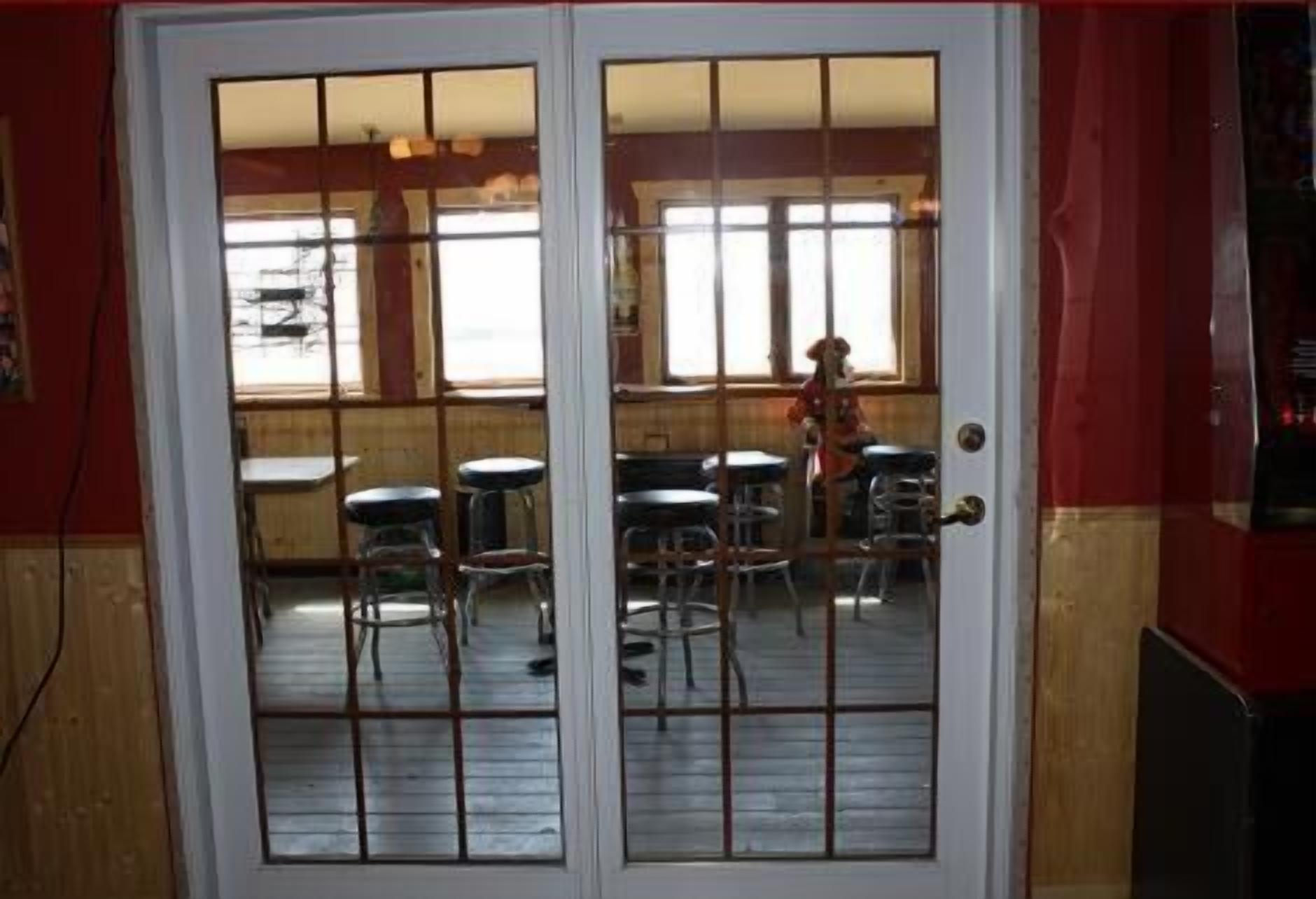 A restaurant with a red and white exterior, a wooden interior, and a view through a glass door.