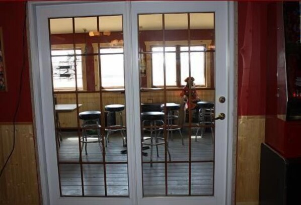 A restaurant with a red and white exterior, a wooden interior, and a view through a glass door. - Sunlac Inn (Lakota)