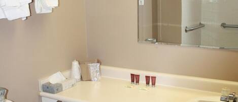 Une salle de bain comprenant des toilettes, un lavabo avec un miroir et un porte-serviettes avec des serviettes.