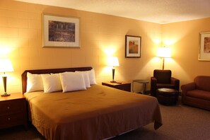 A hotel room with a large bed, two bedside tables, a chair, and a small table.