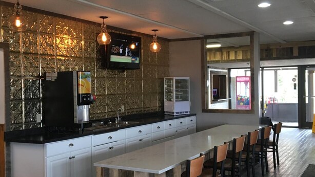 A modern kitchen with a long island counter, white cabinets, and pendant lighting. - Sunlac Inn (Lakota)