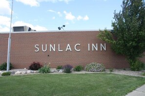 Tiiliseinä, jossa on teksti »SUNLAC INN», joka ilmoittaa liikkeen nimen.