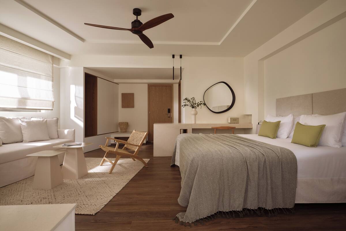 Une chambre d’hôtel moderne équipée d’un grand lit, d’un bureau, d’une chaise et d’un ventilateur de plafond.