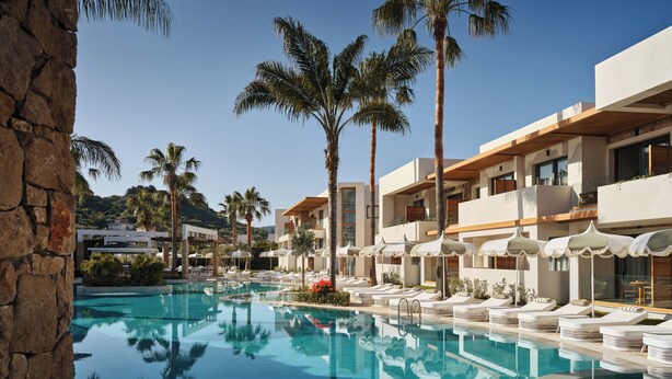 Een resort met een zwembad, palmbomen en moderne gebouwen.