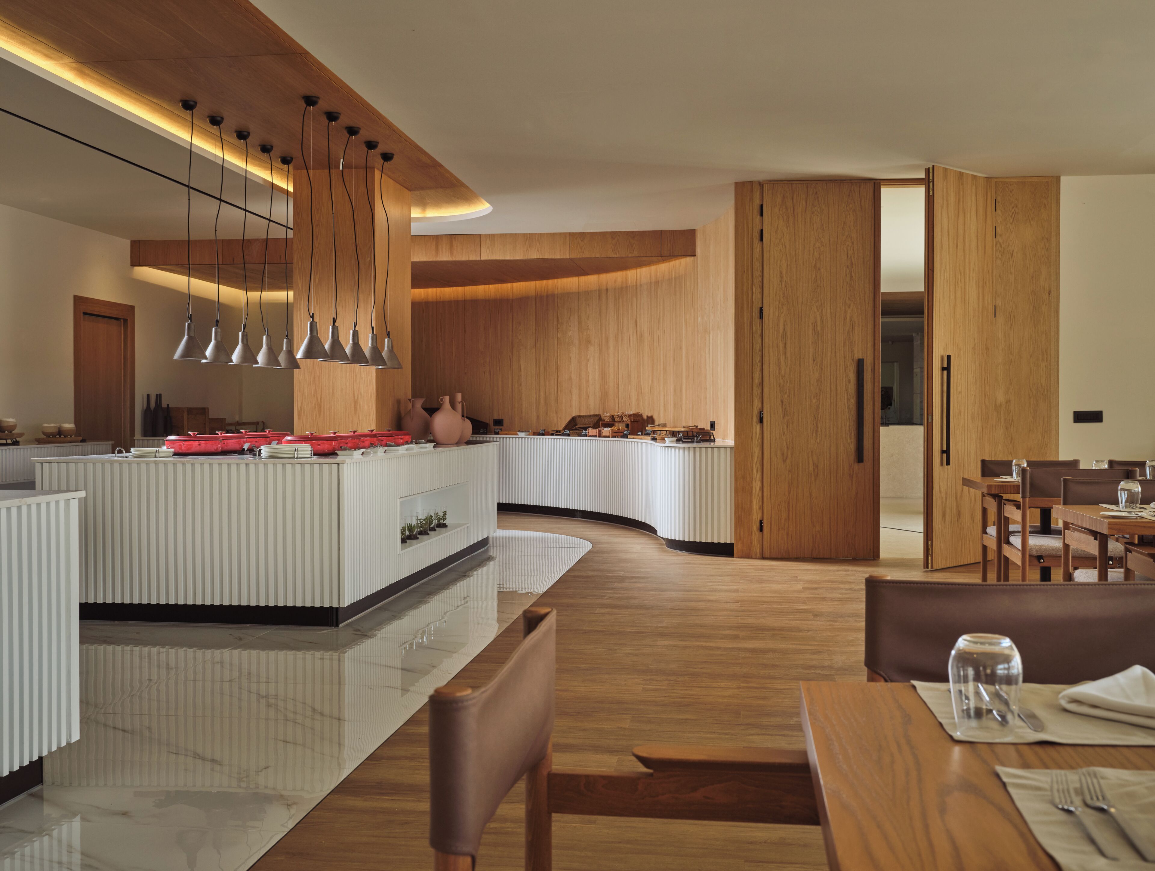 Una cocina moderna con una isla central, iluminación colgante y armarios de madera.