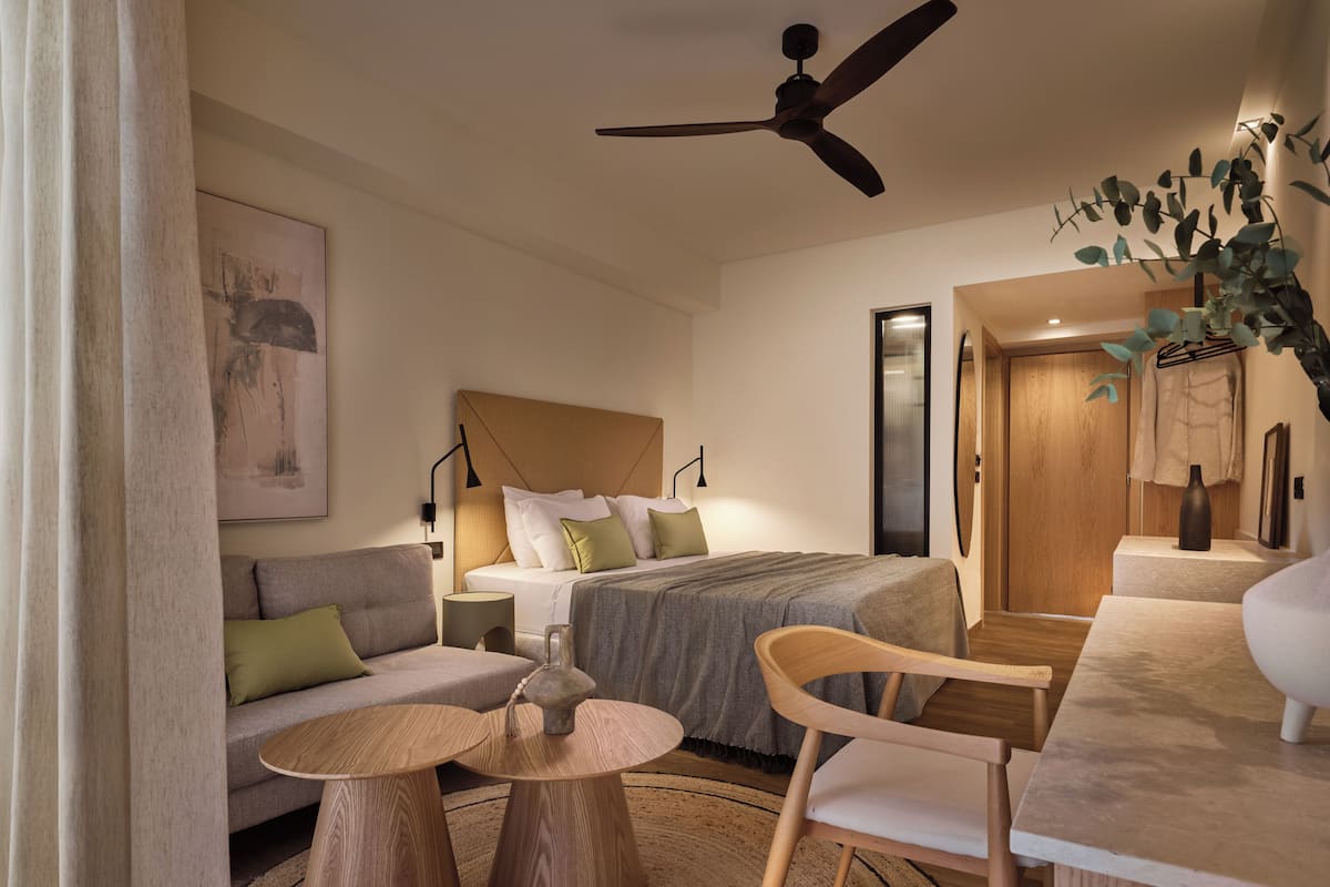 Une chambre d’hôtel moderne équipée d’un lit, d’un canapé, d’une table à manger et d’un ventilateur de plafond.