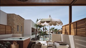 Een terras op het dak met een jacuzzi, rieten meubels en uitzicht op een zwembad en palmbomen.