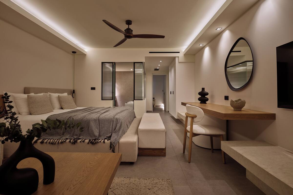 Une chambre moderne comprenant un lit, une table de chevet, une chaise, un bureau et un ventilateur de plafond.