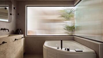 A modern bathroom with a freestanding bathtub, a large mirror, and a window with vertical blinds.