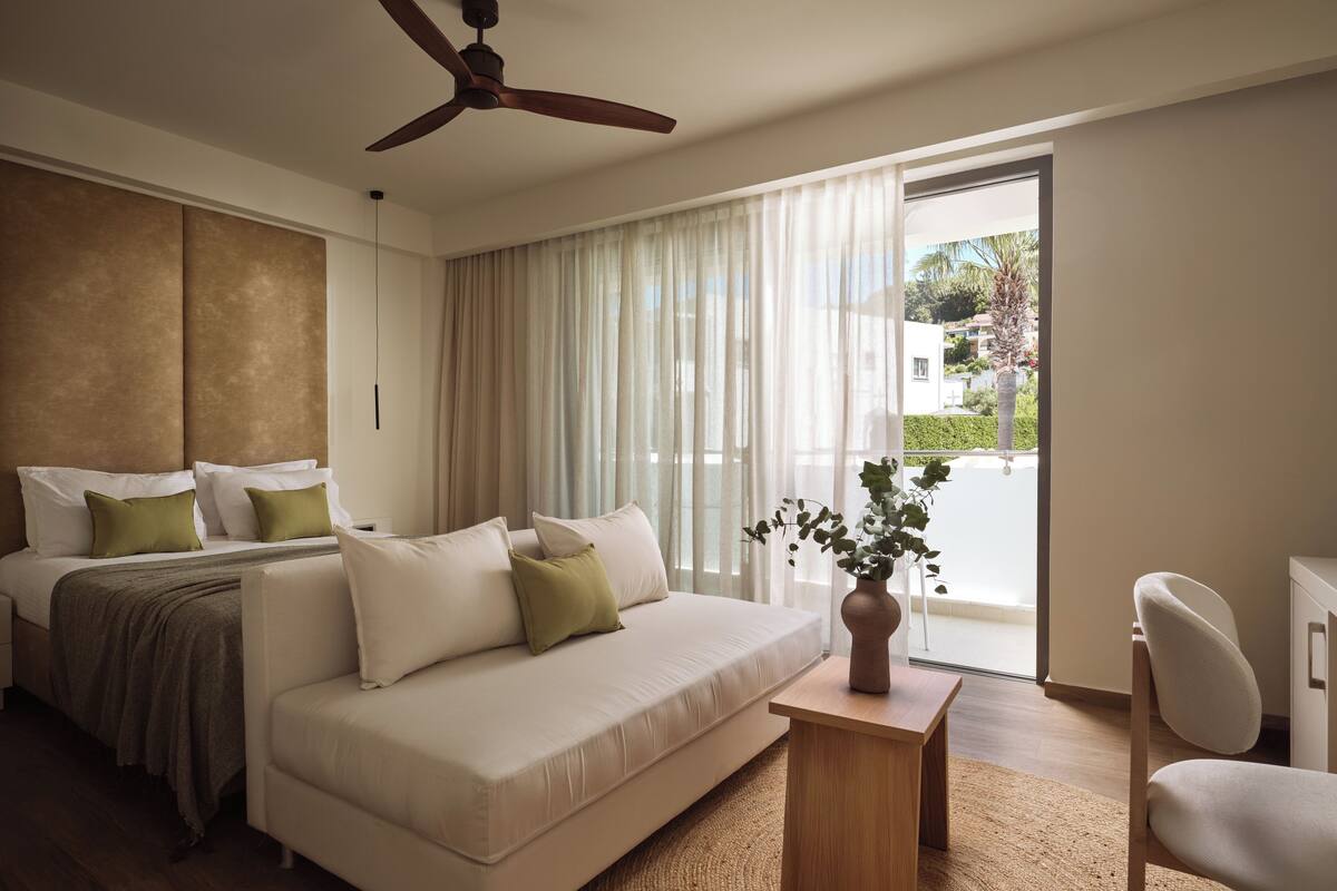Une chambre d’hôtel moderne équipée d’un lit, d’un canapé, d’une table basse et offrant une vue sur l’extérieur.