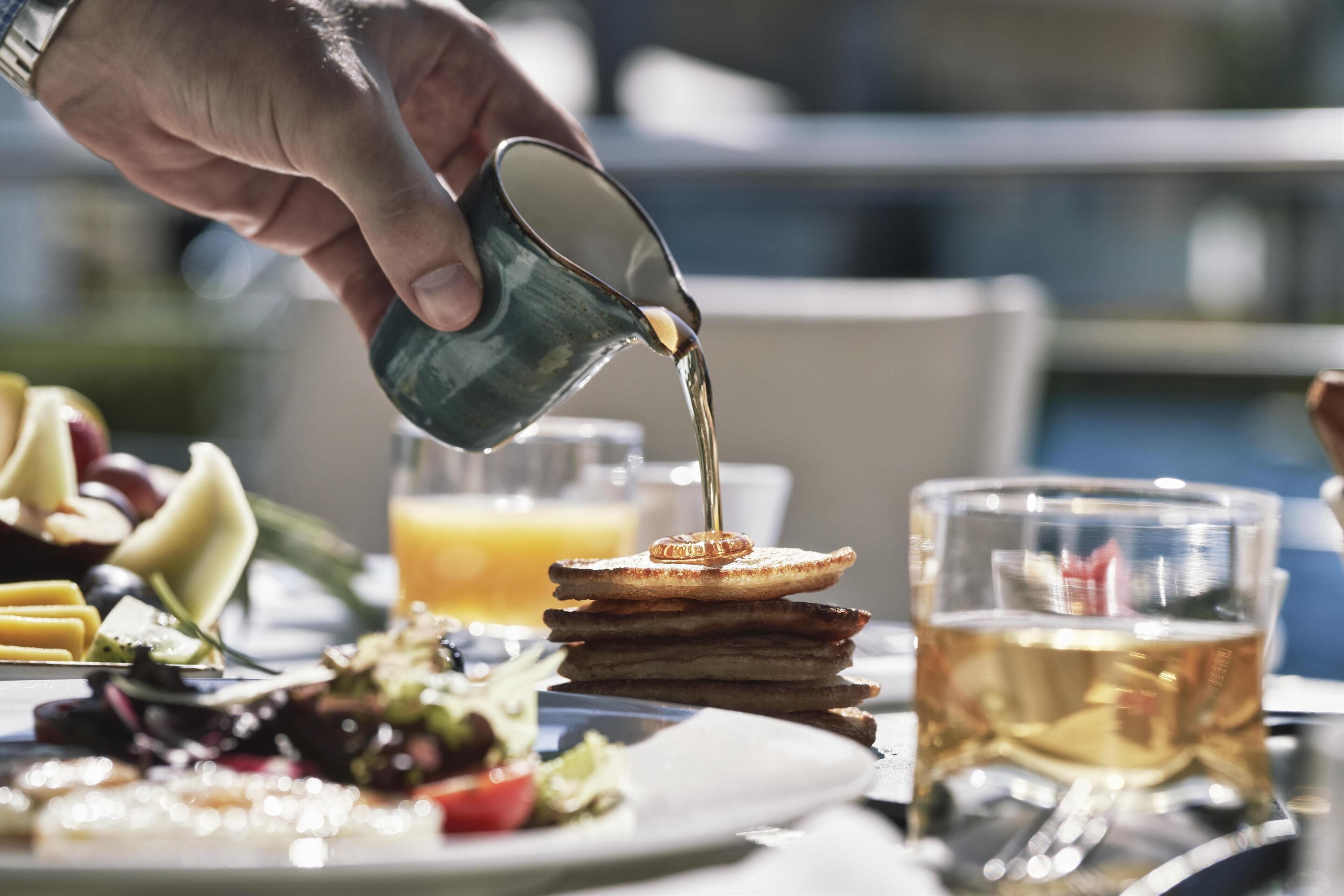 Ein Frühstücksbuffet mit verschiedenen Speisen und Getränken, darunter Toast, Obst und ein Glas Saft.