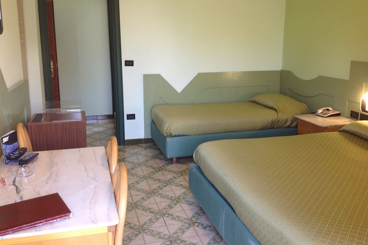 A hotel room with two beds, a desk with a chair, a telephone, and a television.