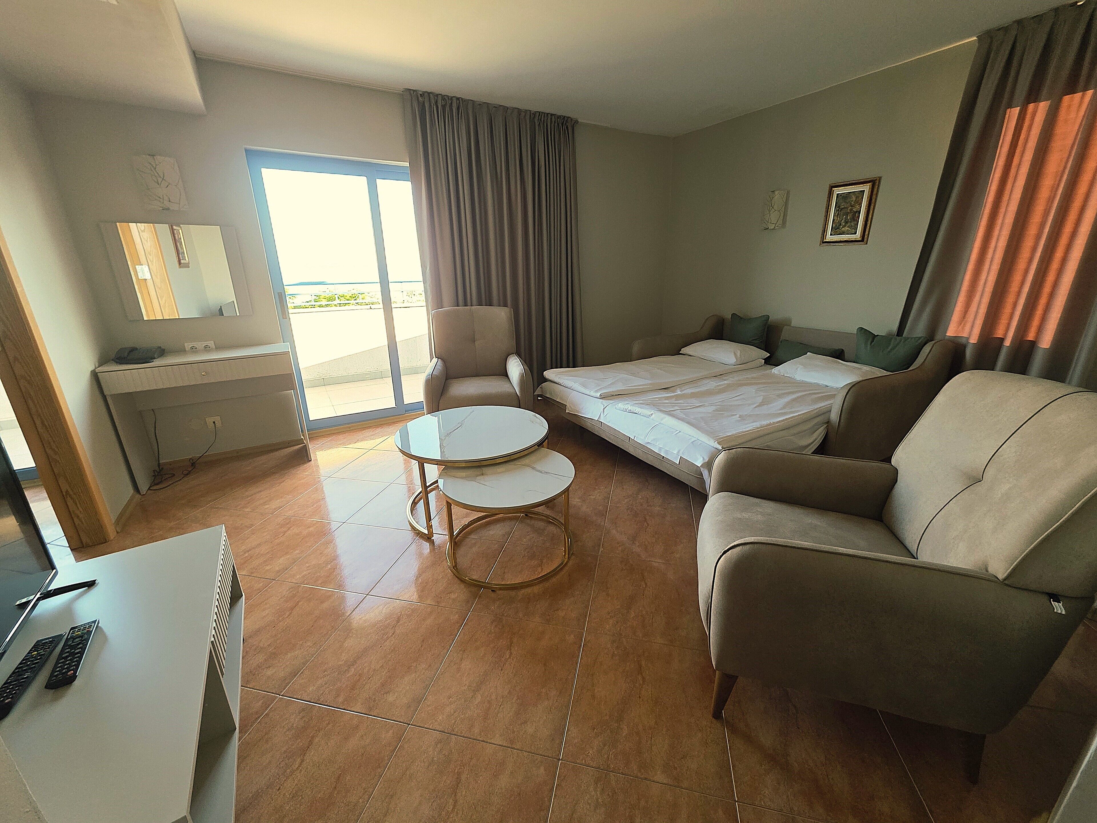 A hotel room with a bed, a sofa, a desk, a chair, and a small table.