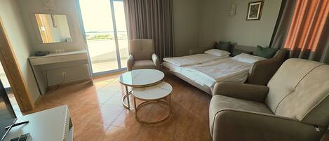 A hotel room with a bed, a sofa, a desk, a chair, and a small table.
