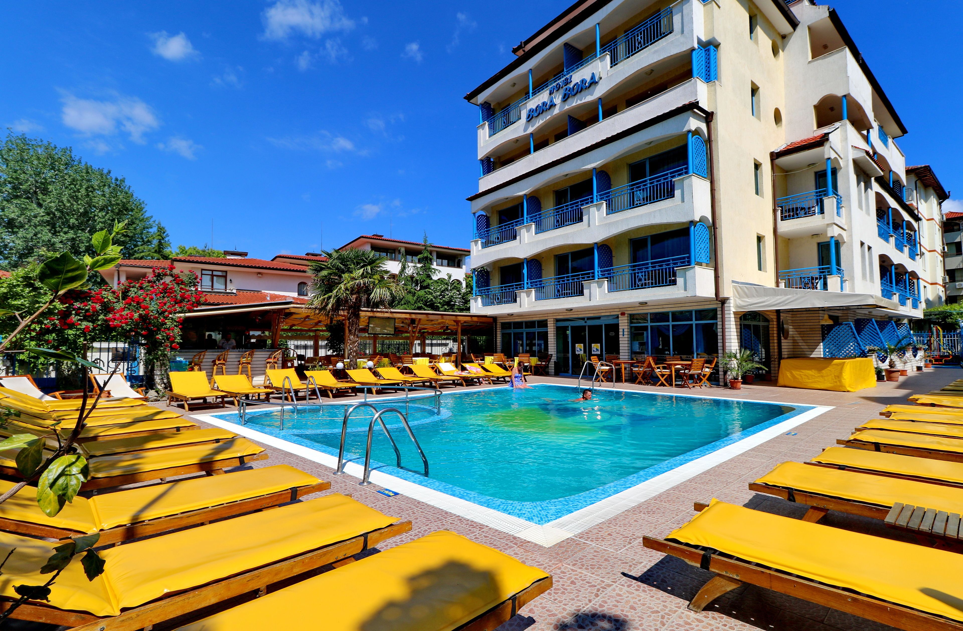 Ein Hotel mit Schwimmbad, umgeben von gelben Liegestühlen.