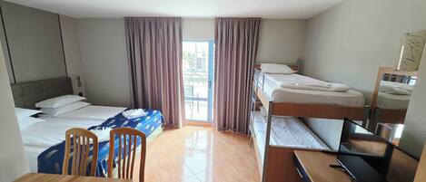 A hotel room with a single bed, a desk with a computer, a chair, and a bunk bed.