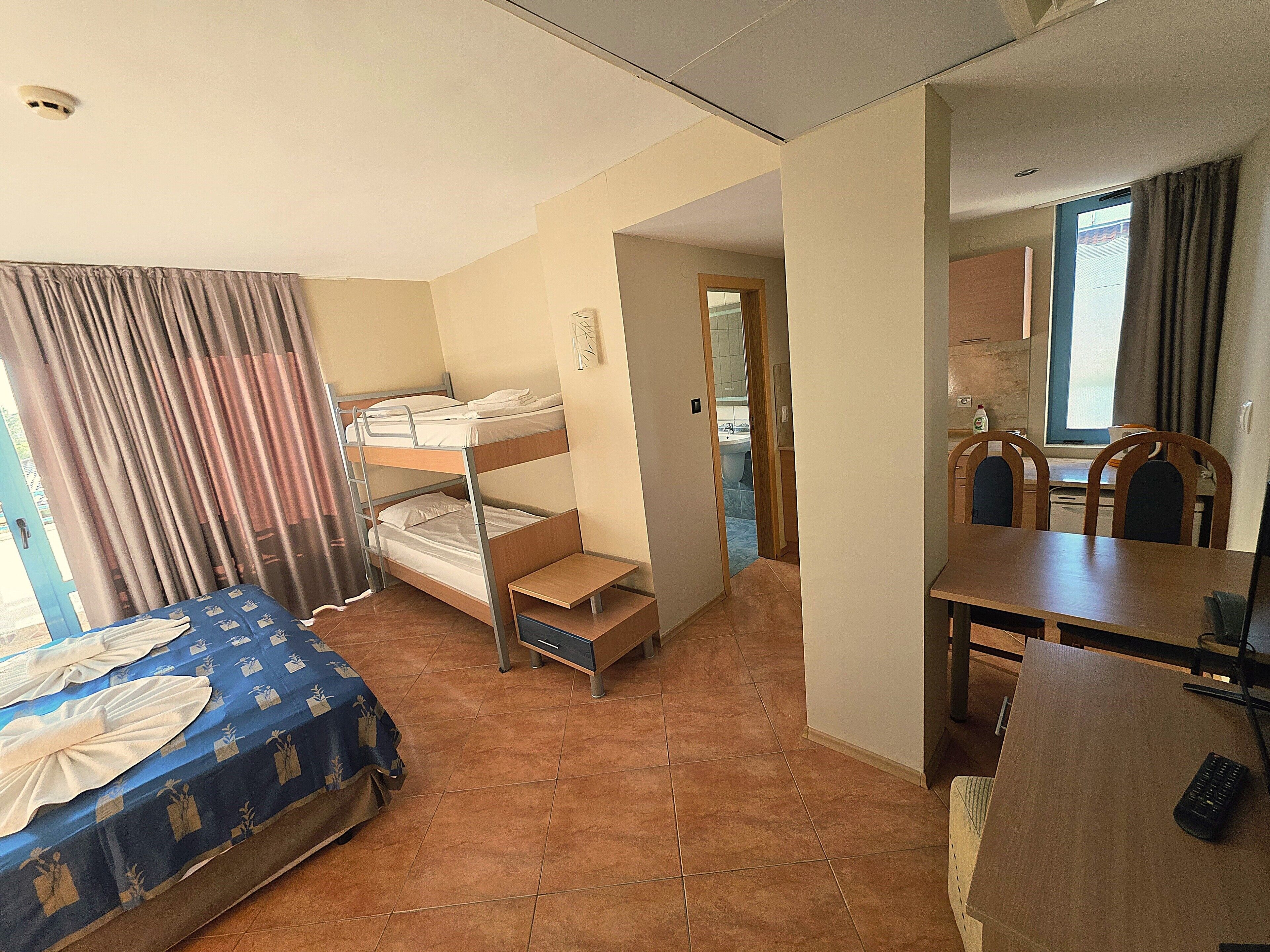 Une chambre de dortoir avec des lits superposés, un bureau et une chaise. On peut apercevoir une salle de bain à travers une porte ouverte.