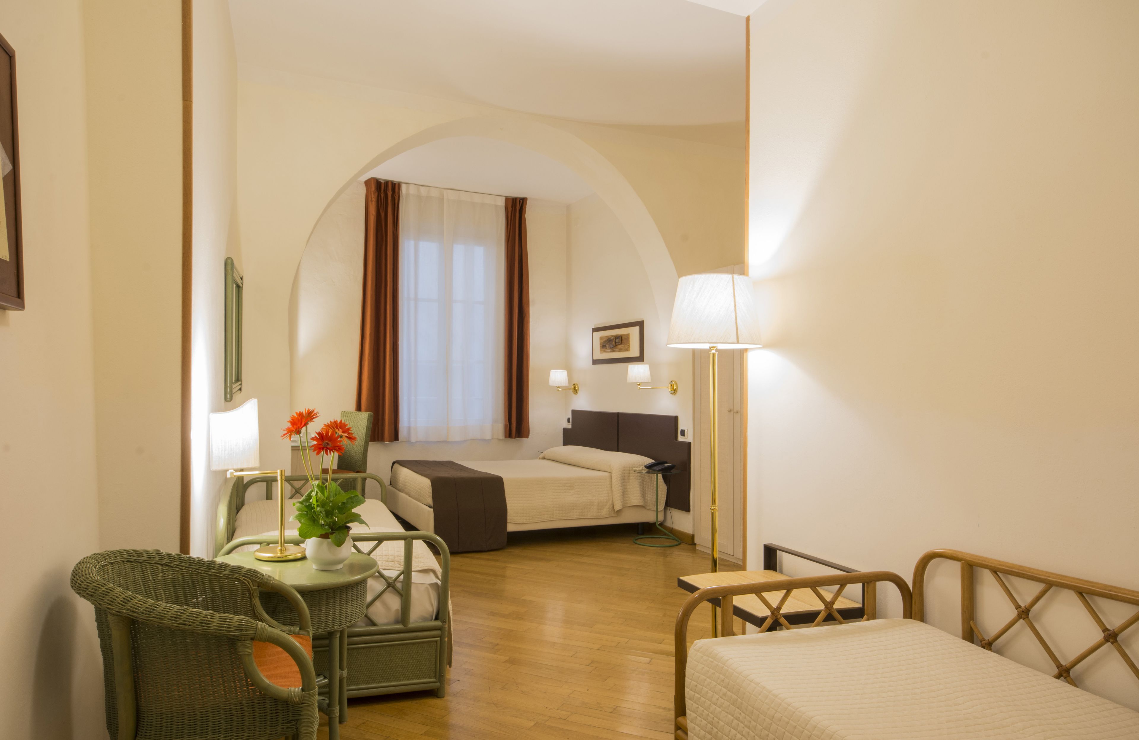 A hotel room with a bed, a chair, a table, and a lamp.
