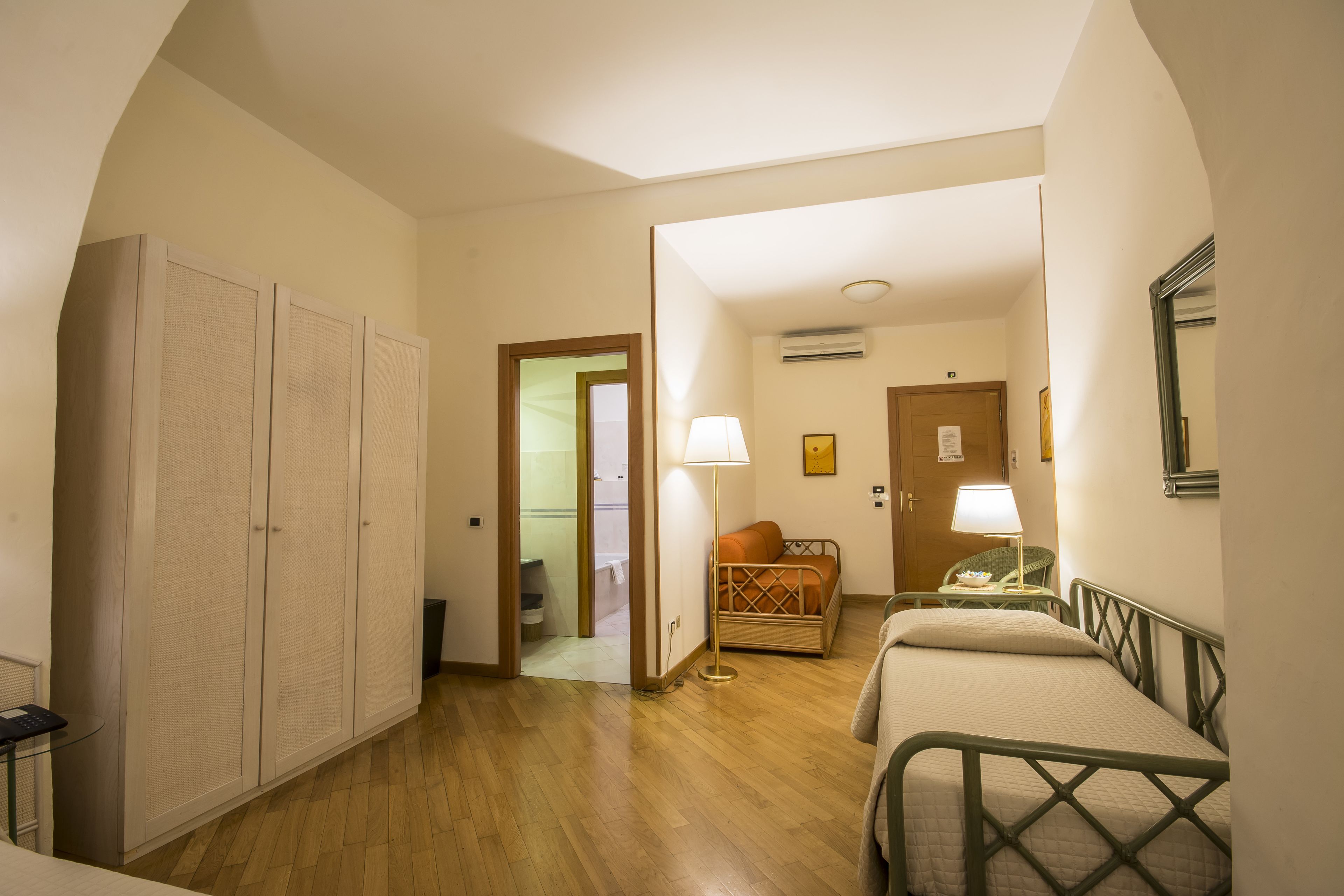 Una habitación de hotel con cama, una silla, un escritorio y un armario.