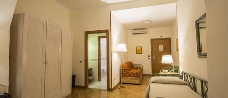 Una habitación de hotel con cama, una silla, un escritorio y un armario.