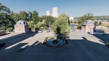 A parking lot with cars, a small building, and a large cooling tower in the background.