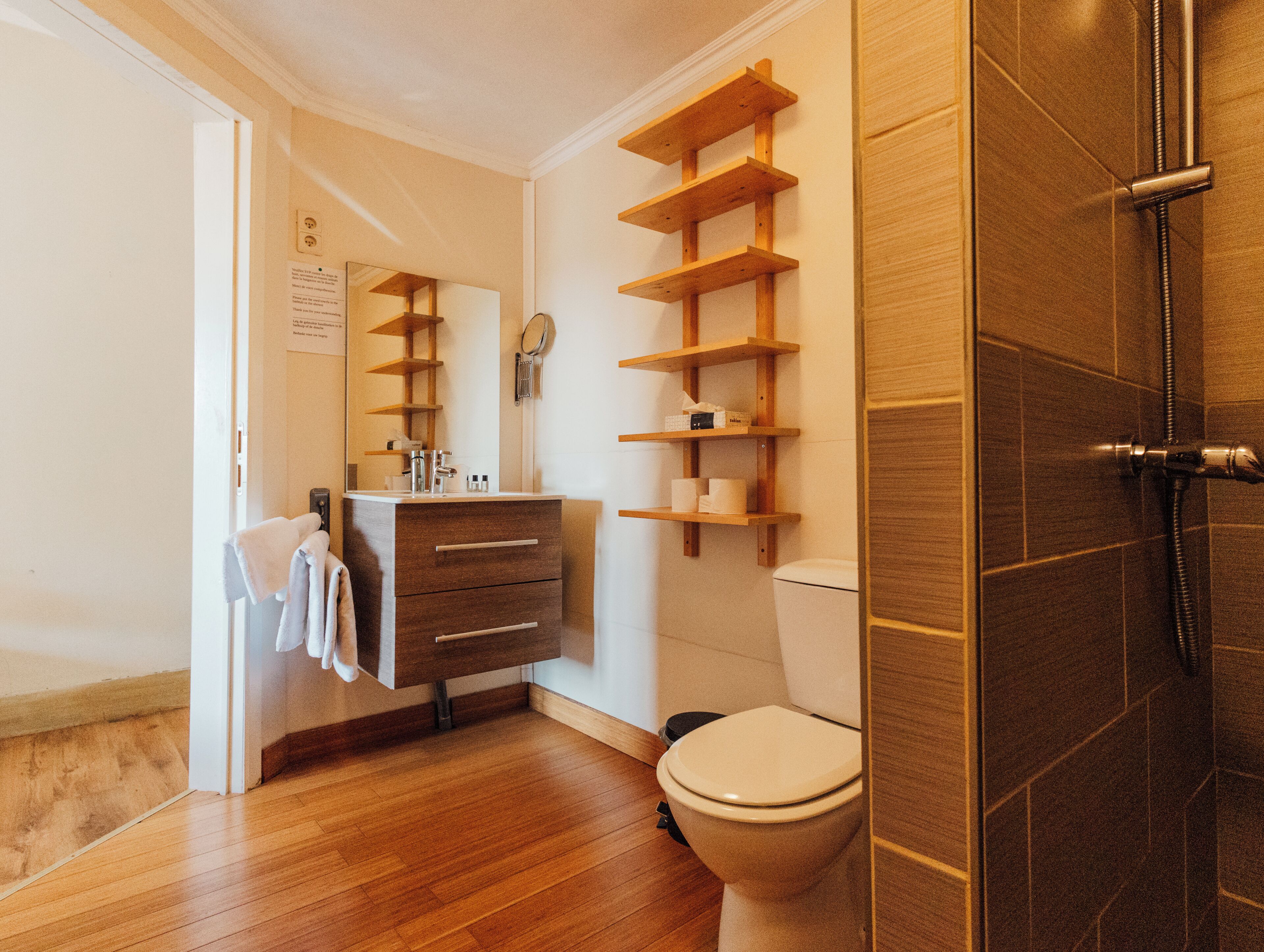 Een badkamer met een houten wastafelmeubel, toilet en douchehoek.