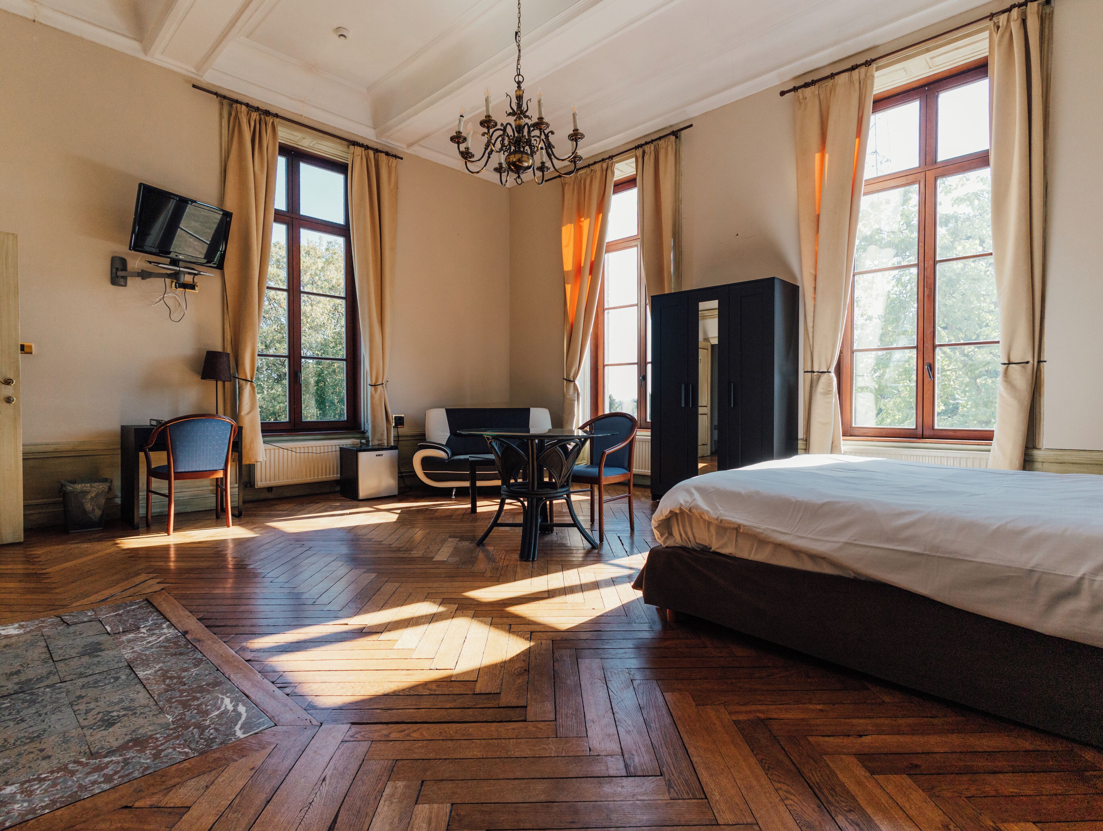 Una habitación de hotel con cama, escritorio, silla, televisor y armario.