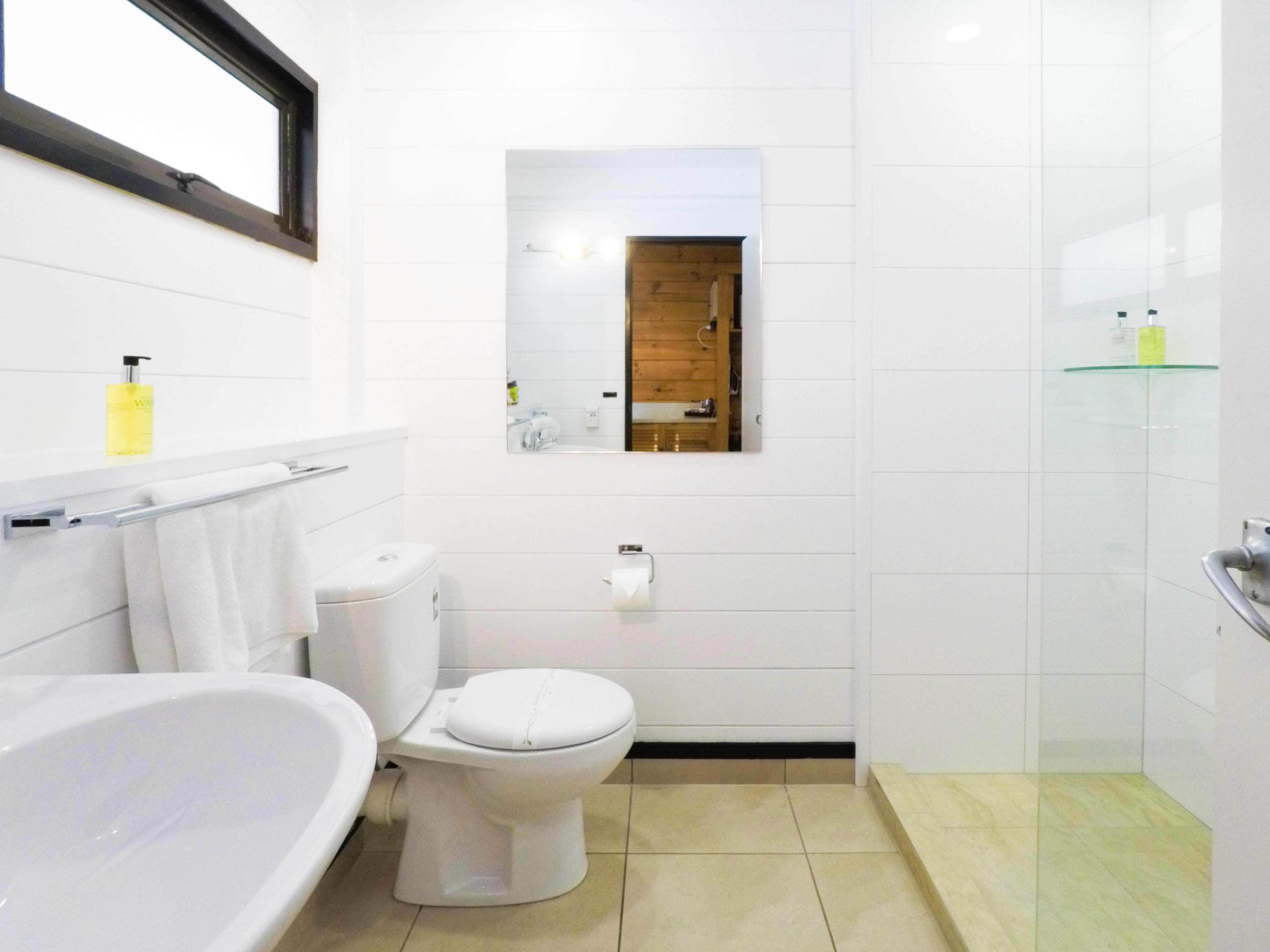 A modern bathroom with a bathtub, toilet, and a glass shower enclosure.