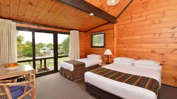 Habitación de cabaña de madera con dos camas, una mesa con fruta y vistas al exterior.