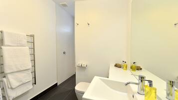 Un baño moderno con lavamanos, espejo y perchero blancos.