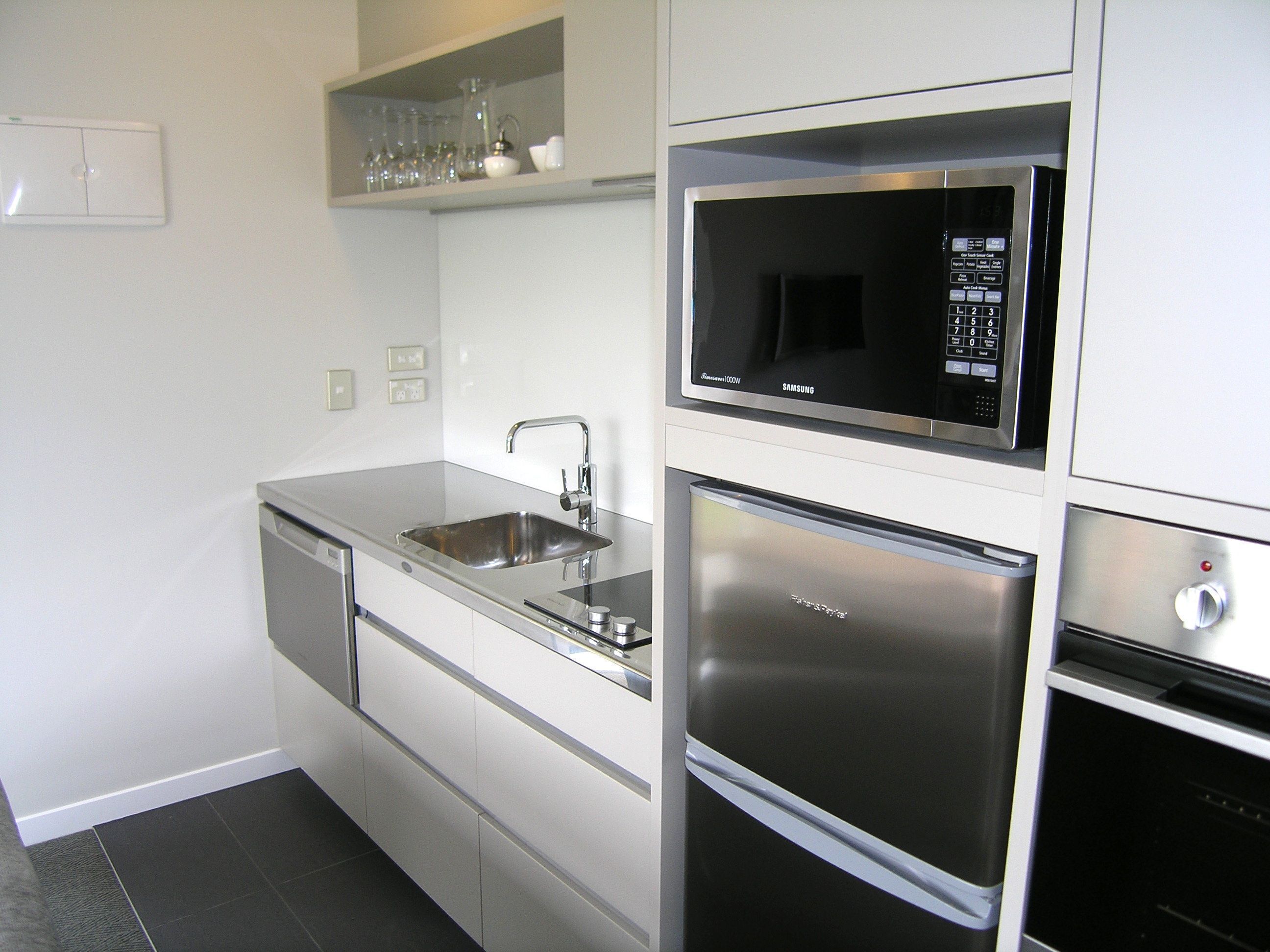 A modern kitchen with a stainless steel refrigerator, a built-in microwave, and a sink.