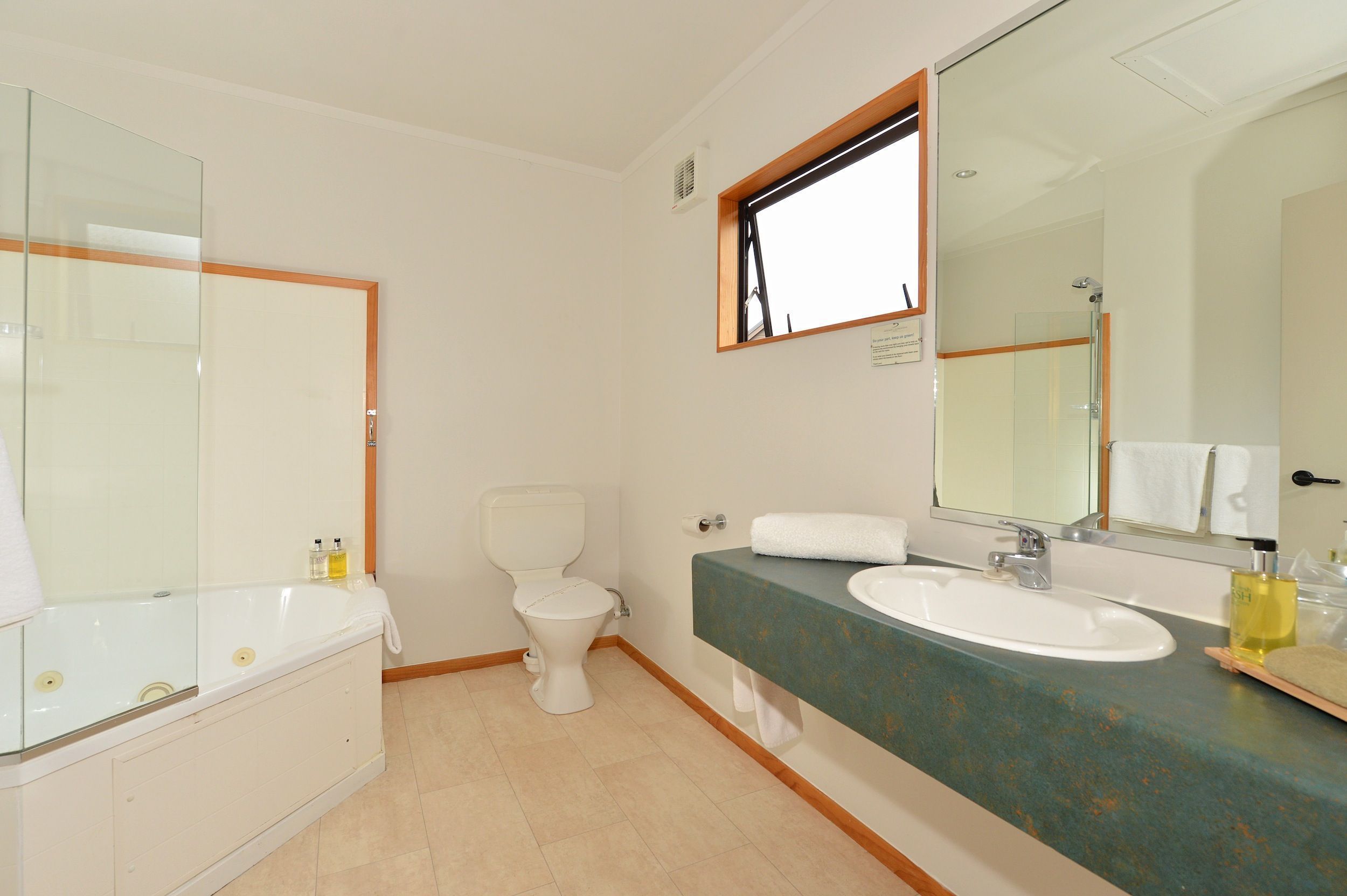 A bathroom with a bathtub, toilet, sink, and large mirror.