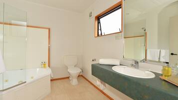 A bathroom with a bathtub, toilet, sink, and large mirror.
