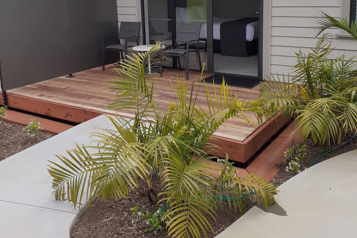 Een modern huis met een overdekte patio, buitenmeubels en een tuin.