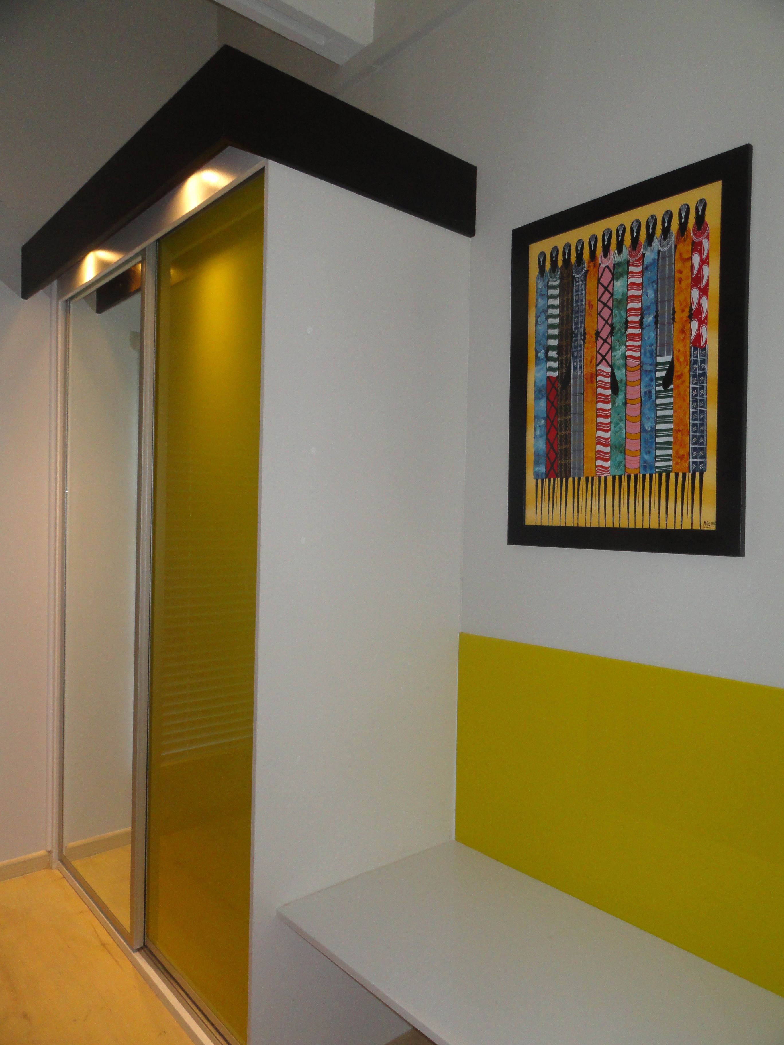 Ein Flur mit einer Bank, einer Glastür und einem farbenfrohen Kunstwerk an der Wand.