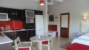 A compact hotel room with a kitchenette, a dining area, and a bed. - Bushwillow Collection (Hluhluwe)