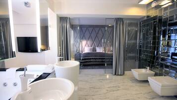 Uma casa de banho de hotel moderna, com um espelho grande, duas lavatórios, uma banheira e um chuveiro amplo.