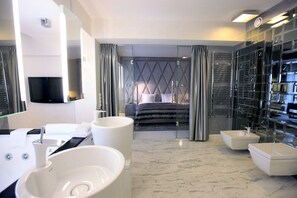 Un baño de hotel moderno con un espejo grande, dos lavamanos, una bañera y una ducha a ras de suelo.