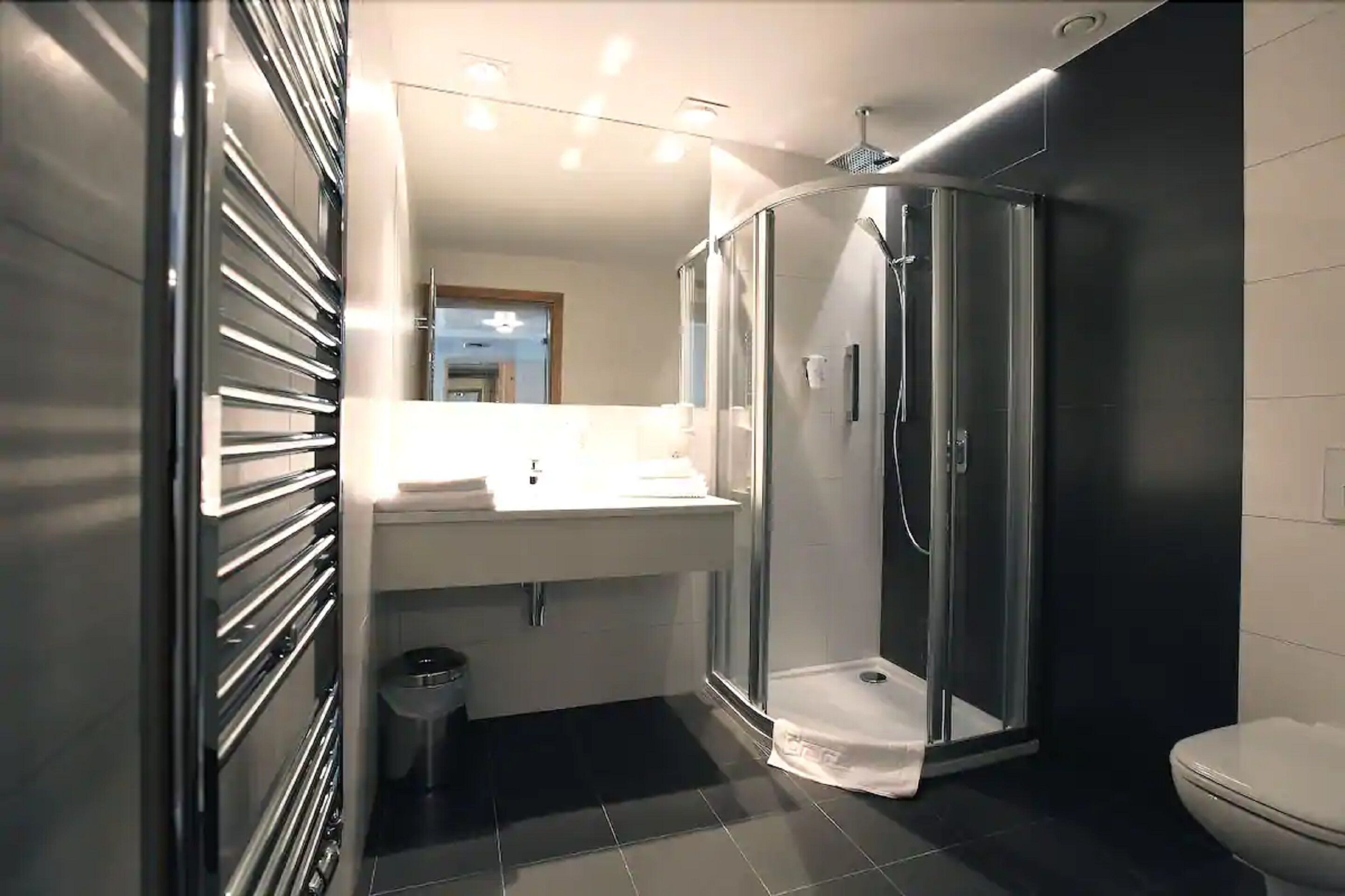 A modern bathroom with a glass-enclosed shower, a white sink, and a toilet.