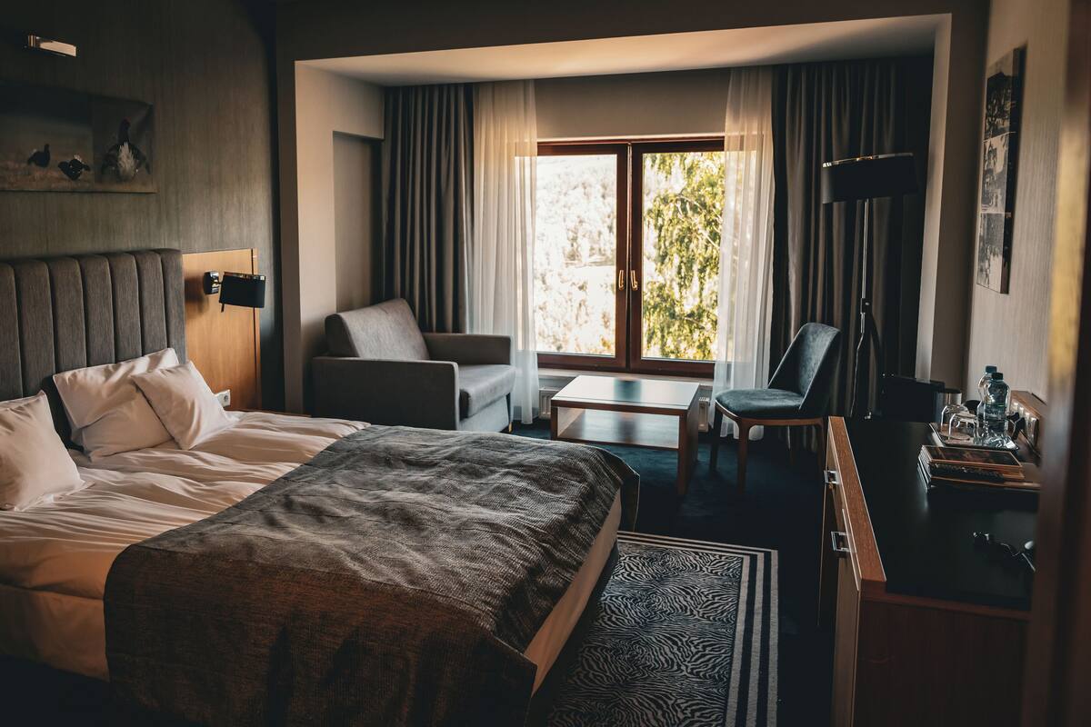A hotel room with a large bed, a desk, a chair, and a view of the outdoors.