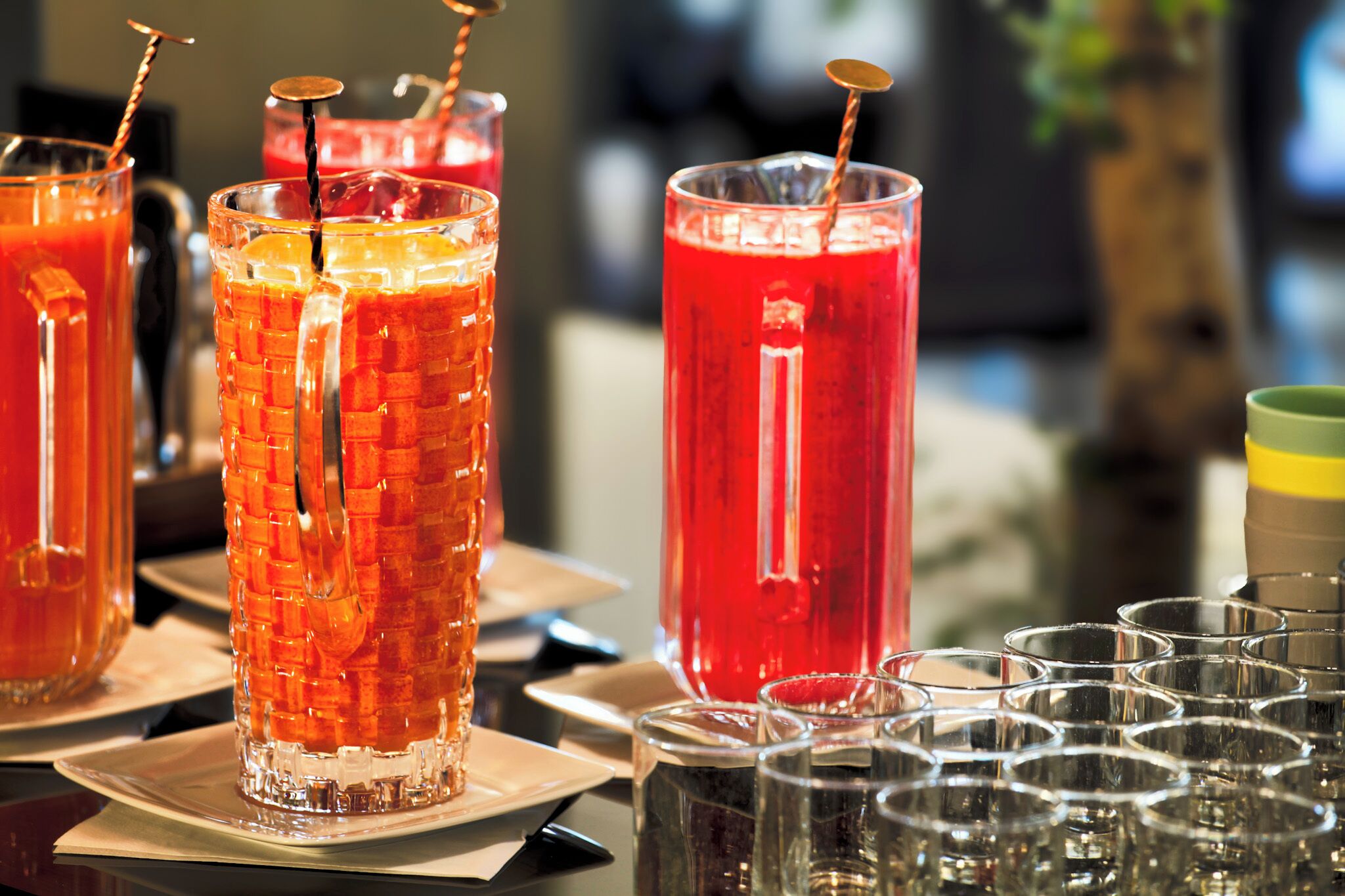 A bar setting with multiple glasses of beverages, some with straws and others without.
