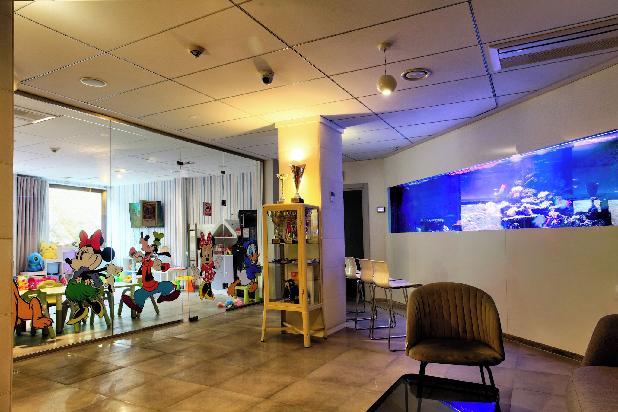 A children's play area with Disney characters, a trophy display, and a large aquarium.