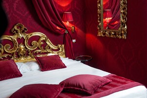 Une chambre luxueuse avec un grand lit à baldaquin richement décoré, des rideaux rouges et un miroir avec un cadre doré.