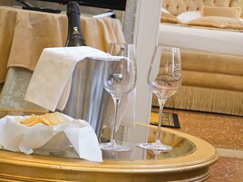 Una botella de champán, dos copas y una cesta de aperitivos sobre una bandeja en una habitación de hotel.