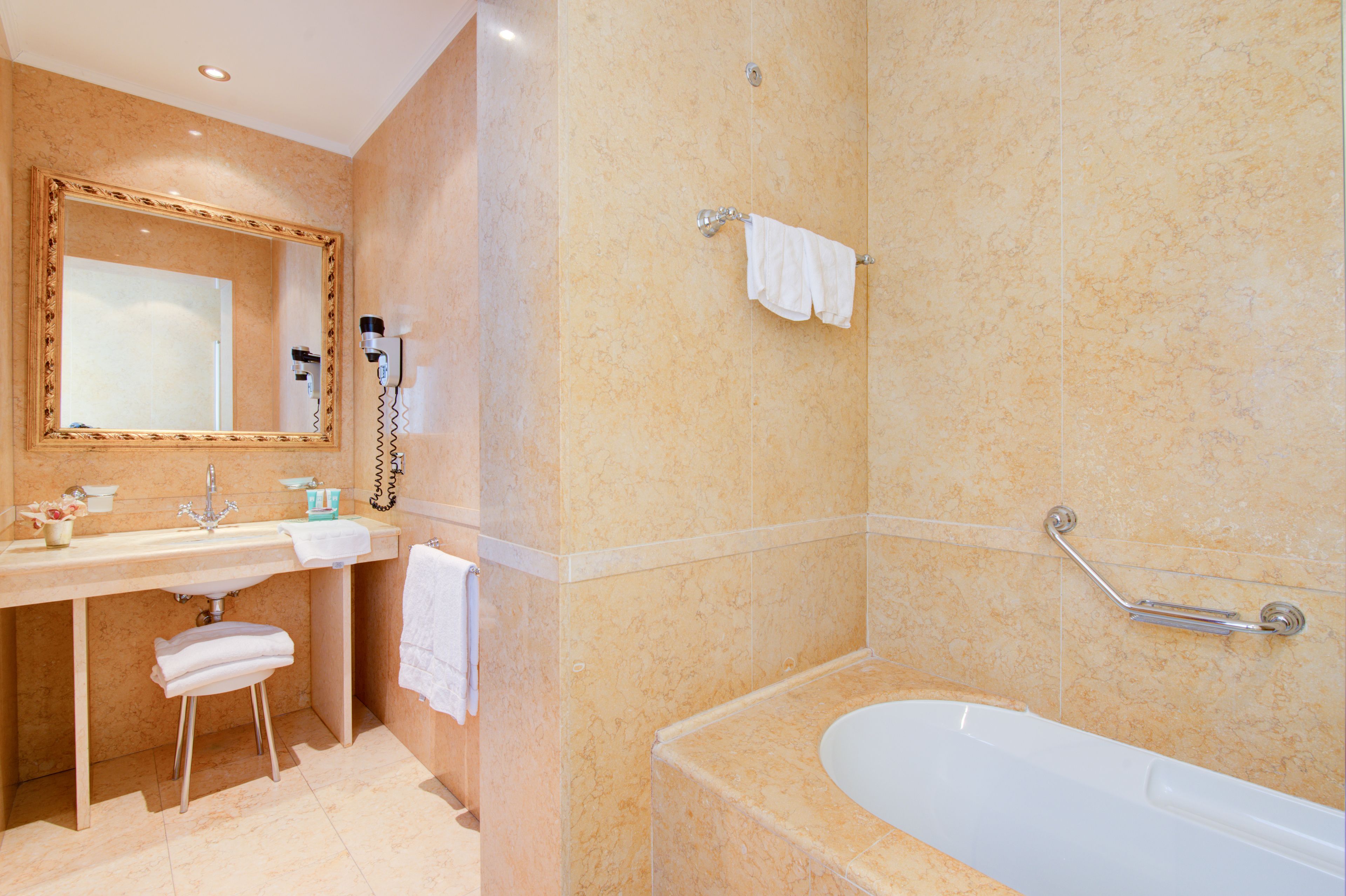 Une salle de bain équipée d’un lavabo, d’un miroir, d’un porte-serviettes et d’une baignoire.