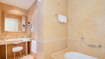 Un baño con lavamanos, espejo, toallero y bañera.