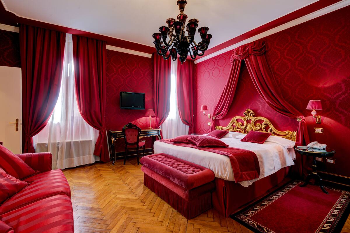 Ein rot eingerichtetes Schlafzimmer mit Bett, Schreibtisch und Fernseher.