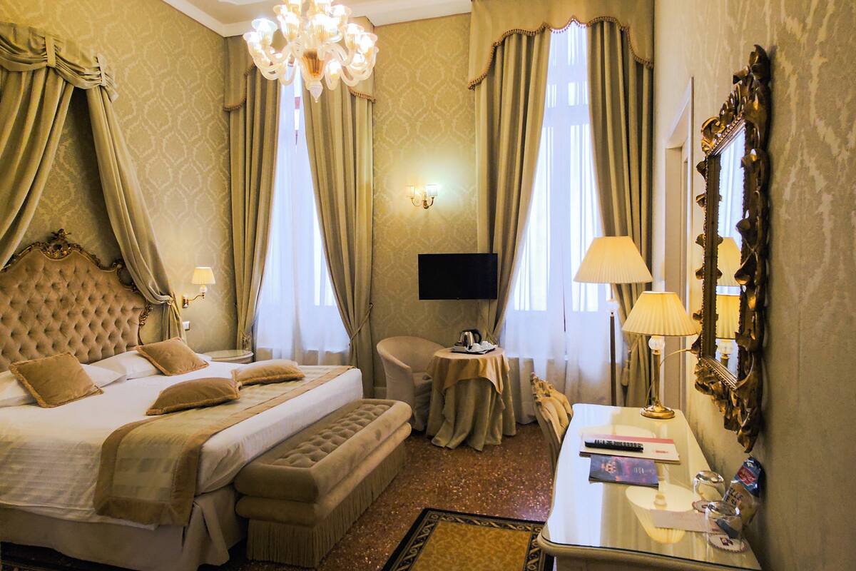 Ein Hotelzimmer mit einem großen Bett, einem Schreibtisch mit Stuhl, einem Fernseher und einem Spiegel.